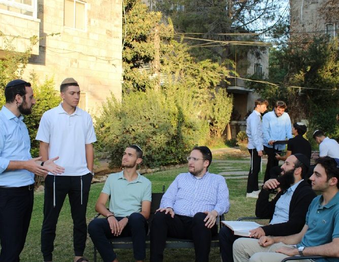 Rebbeim and talmidim talking on the campus lawn