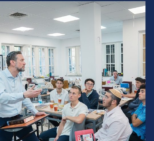 A Rebbe giving shiur to a full classroom in the Beit Midrash