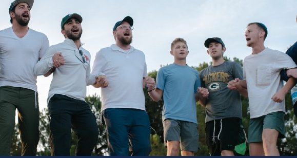 Talmidim singing with arms around each other outdoors