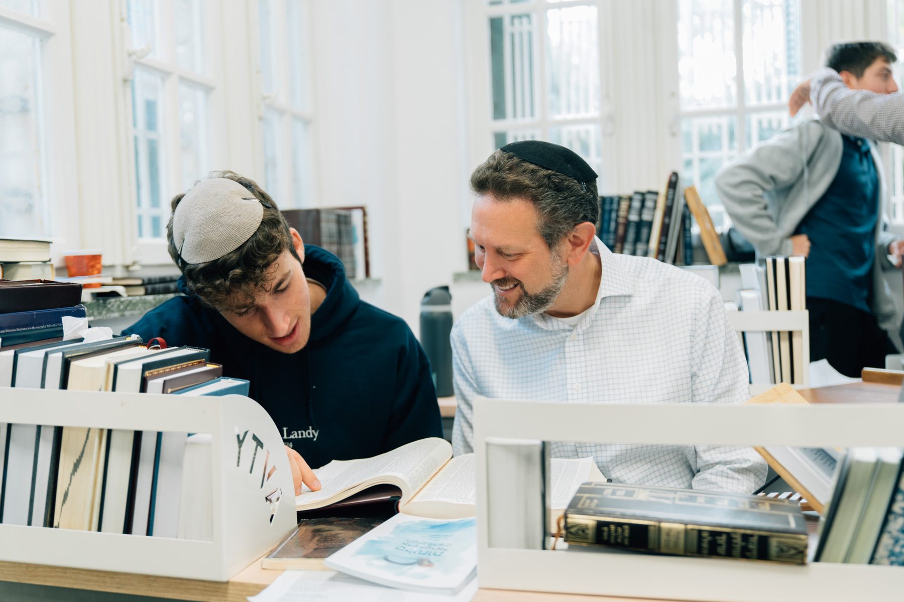 A Rebbe and a talmid learning over a sefer in the Beit Midrash